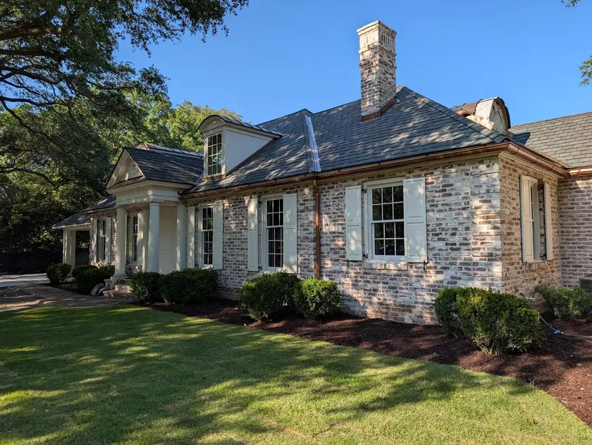 Restored limewashed brick residence with rebuilt chimney under mature oaks