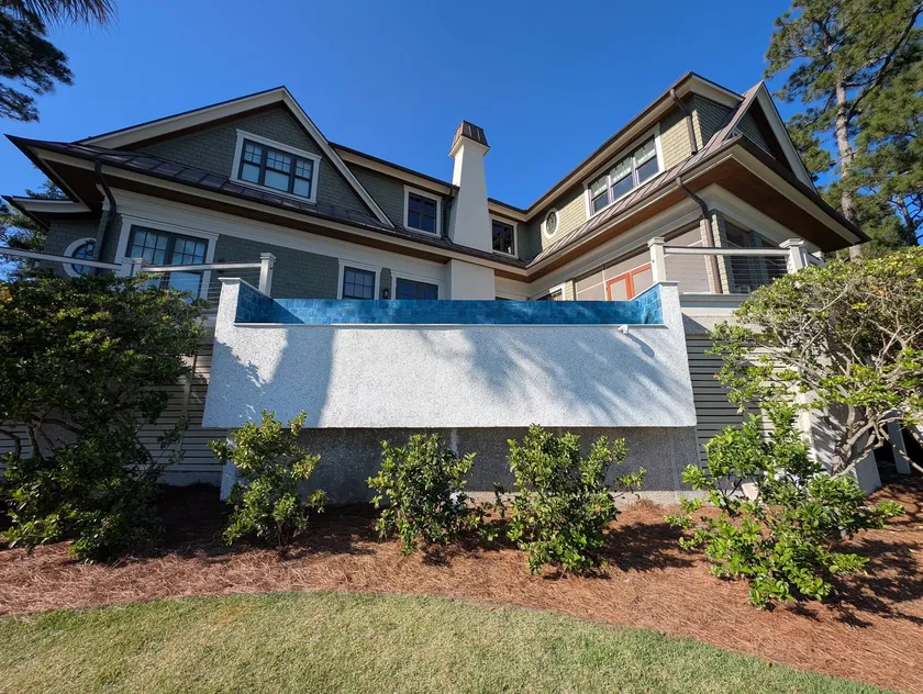 Refinished pool wall, one uniform face beneath the rebuilt blue glass tile edge