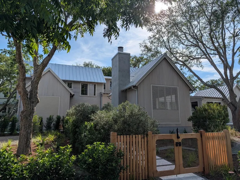 Completed modern Lowcountry home with standing seam metal roof behind a cedar gate