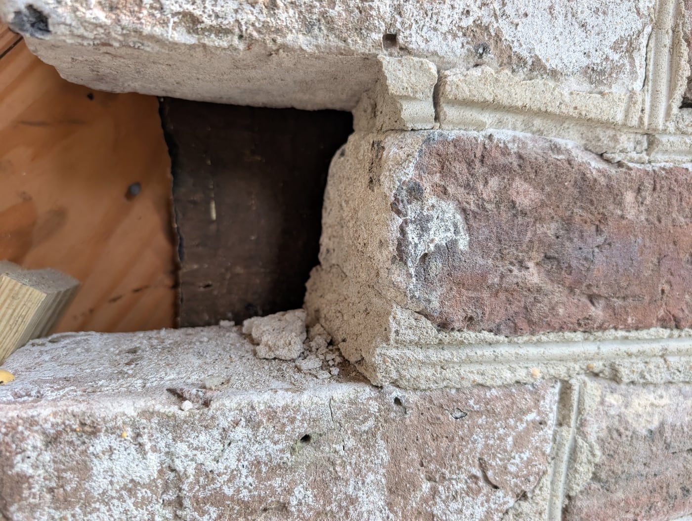 Old brick wall opened at a course, a pocket cut to receive new brick
