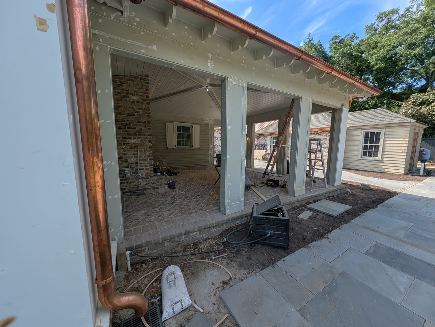 Porch with a copper downspout, brick floor and bluestone terrace in progress