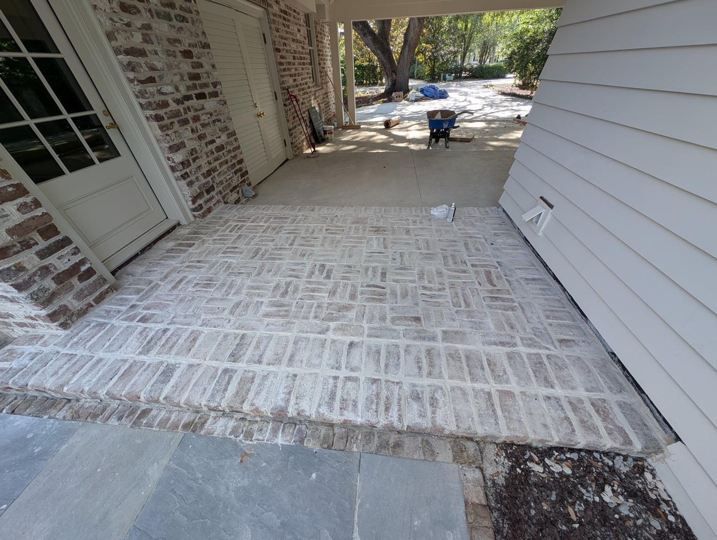 Finished washed brick floor in a basketweave pattern beneath a porch, bluestone terrace in front
