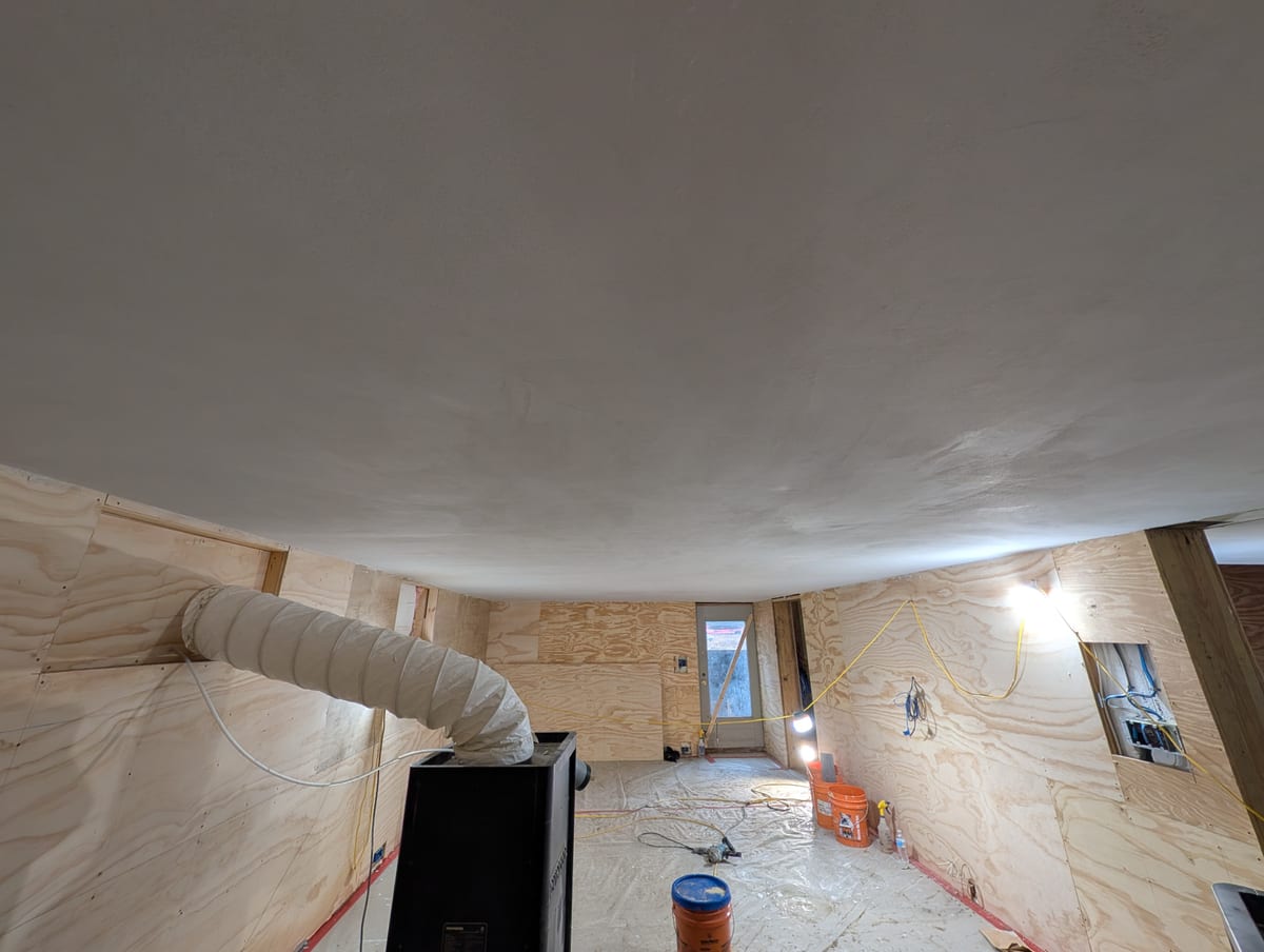 Room prepared for plaster, floor protected, work lights and air handling in place beneath the ceiling