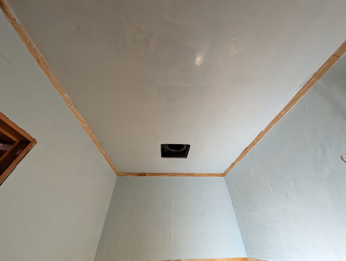 Finished room with tinted plaster walls and a plaster ceiling framed by wood trim