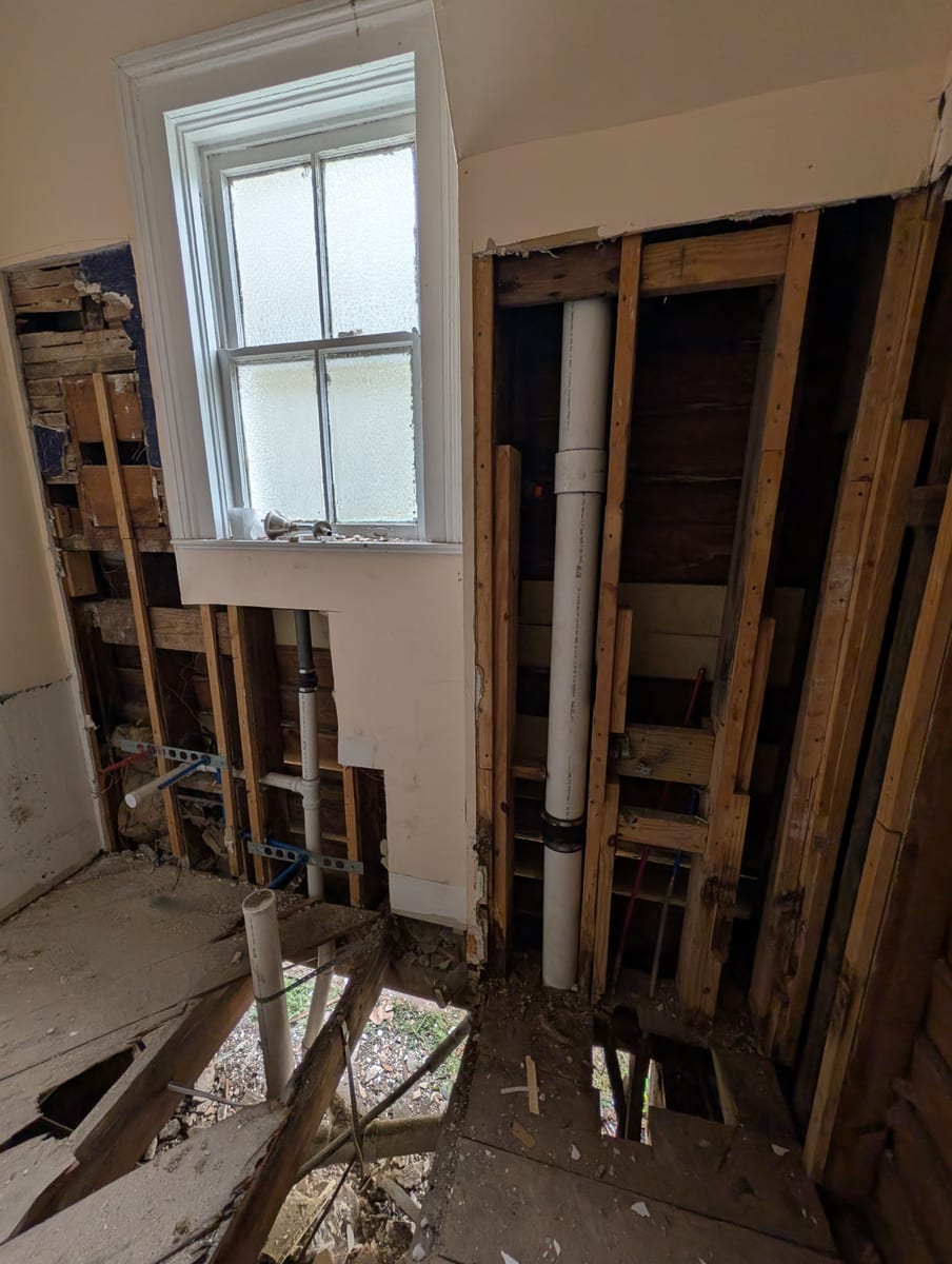 Bathroom walls and floor opened to the framing, drain and supply lines exposed